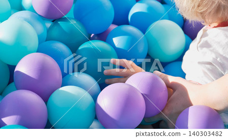 Toddler's hands playing in brightly colored ball pit, enjoying sensory childhood fun Toddler's hands playing in brightly colored ball pit, enjoying sensory childhood fun 140303482