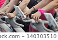 Close up of a group of women exercising on stationary bikes in a fitness class 140303510