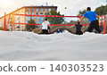 A group of young men are playing beach volleyball in a large city. 140303523