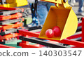 Yellow toy excavator bucket with red plastic balls at a playground 140303547