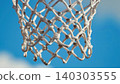 Close up of a basketball net outdoors against a bright blue sky 140303555
