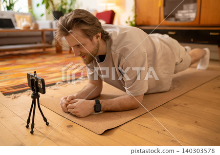 Young man having online yoga class and exercising at home Young man having online yoga class and exercising at home 140303578