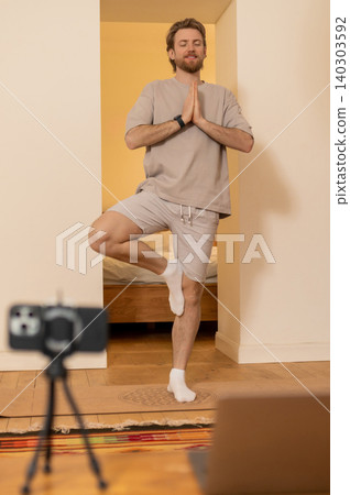 Young caucasian doing yoga and standing in a tree pose Young caucasian doing yoga and standing in a tree pose 140303592