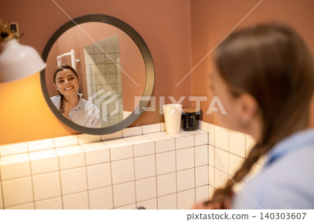 Cute young woman having morning procedures in the bathroom and looking happy Cute young woman having morning procedures in the bathroom and looking happy 140303607