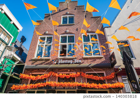 Amsterdam, Netherlands, 22.04.2026 - Hertog jan signs on traditional dutch brick building facade decorated with festive orange bunting flags for koningsdag celebration in zaandam, netherlands Amsterdam, Netherlands, 22.04.2026 - Hertog jan signs on traditional dutch brick building facade decorated with festive orange bunting flags for koningsdag celebration in zaandam, netherlands 140303818