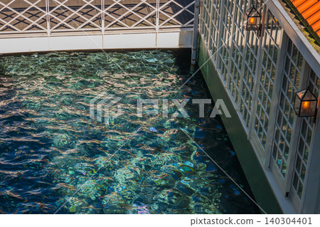 Water surface ripple in traditional dutch canal with wooden pavilion house windows, scenic clear turquoise river flow next to terrace under sunlight, travel and leisure concept Water surface ripple in traditional dutch canal with wooden pavilion house windows, scenic clear turquoise river flow next to terrace under sunlight, travel and leisure concept 140304401