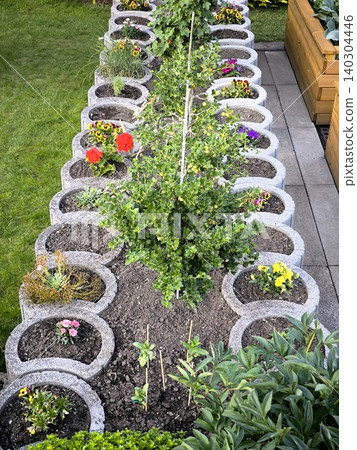 Multi-tiered round flowerbed made of concrete planters in the garden Multi-tiered round flowerbed made of concrete planters in the garden 140304446