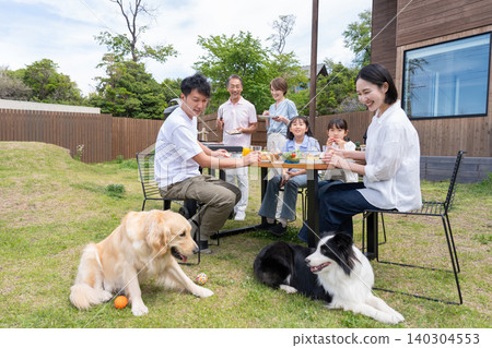 A three-generation family and their dog having a barbecue in the garden. A three-generation family and their dog having a barbecue in the garden. 140304553