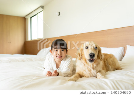 一個女孩在床上和狗玩耍 一個女孩在床上和狗玩耍 140304690