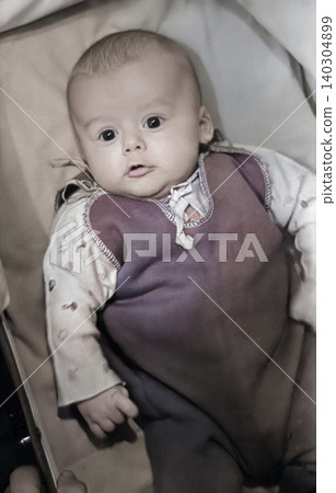 Vintage baby with an attentive gaze in a retro stroller portrait Vintage baby with an attentive gaze in a retro stroller portrait 140304899