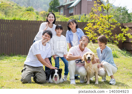 A three-generation family playing with their dog in the yard A three-generation family playing with their dog in the yard 140304923