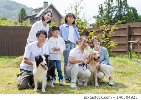 A three-generation family playing with their dog in the yard A three-generation family playing with their dog in the yard 140304925