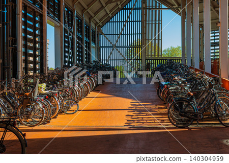 Bicycle parking station in Netherlands with rows of parked bikes, contemporary indoor eco transport garage building with sunny shadows on floor in Zaandam, Dutch lifestyle concept Bicycle parking station in Netherlands with rows of parked bikes, contemporary indoor eco transport garage building with sunny shadows on floor in Zaandam, Dutch lifestyle concept 140304959