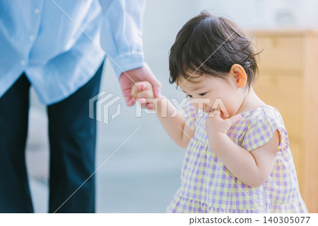A child walking hand in hand with their mother. 140305077