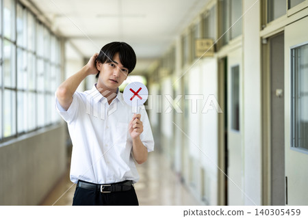 一名男學生摸著自己的頭髮 140305459