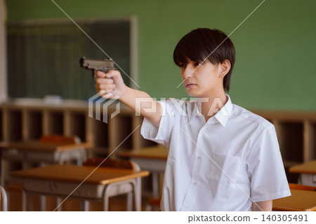 A boy holding a gun in a classroom A boy holding a gun in a classroom 140305491