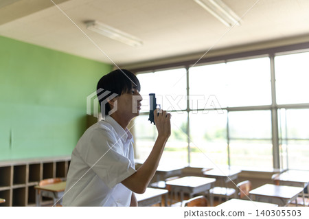 A boy holding a gun in a classroom A boy holding a gun in a classroom 140305503
