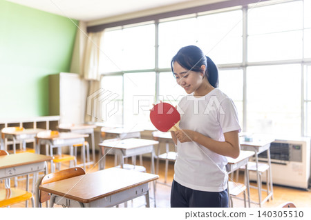 教室裡，一名女子拿著乒乓球拍。 140305510