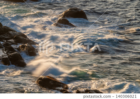 Rocky reefs and waves shining in the setting sun; a beautiful evening view of Yakushima, where gods reside (winter) Rocky reefs and waves shining in the setting sun; a beautiful evening view of Yakushima, where gods reside (winter) 140306021