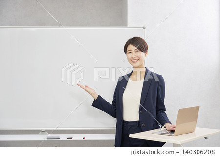 Businesswoman pointing at whiteboard with palm of hand in conference room 140306208