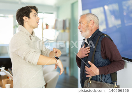 Young man scolding elderly male colleague for being late to office Young man scolding elderly male colleague for being late to office 140306366