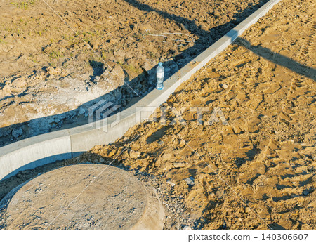 Concrete curb and manhole on new construction site with plastic bottle 140306607