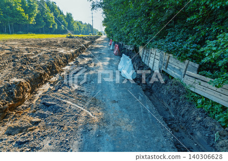 Rural dirt road under construction bordered by forest and field Rural dirt road under construction bordered by forest and field 140306628