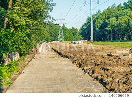 Rural powerline construction site with new concrete access road beside forest Rural powerline construction site with new concrete access road beside forest 140306629