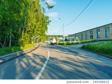 Quiet suburban road flanked by birch trees and low industrial building 140306632