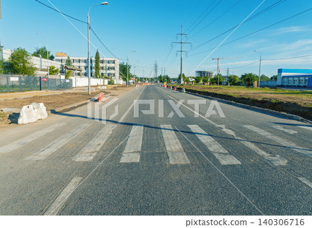 Empty urban street with worn pedestrian crosswalk under clear blue sky 140306716