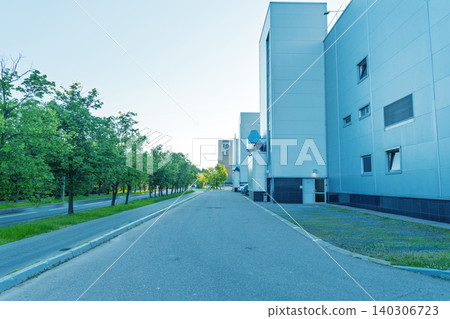 Empty industrial street with modern factory buildings and tree-lined sidewalk Empty industrial street with modern factory buildings and tree-lined sidewalk 140306723