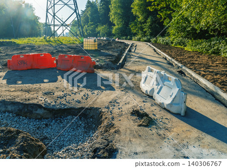 Road construction site with plastic barriers and gravel path in wooded area Road construction site with plastic barriers and gravel path in wooded area 140306767