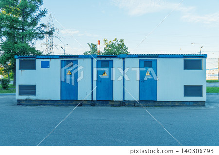 Row of blue metal utility transformer cabinets with warning signs 140306793