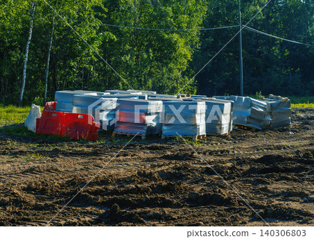 Stacked concrete road barriers on cleared construction site near forest Stacked concrete road barriers on cleared construction site near forest 140306803