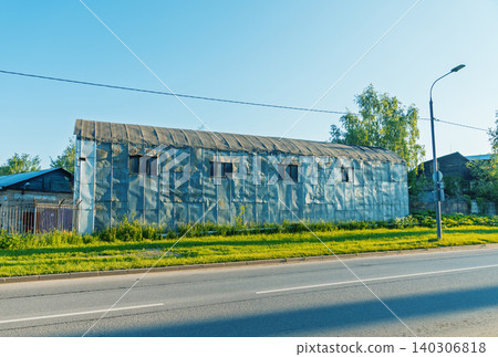 Weathered corrugated metal warehouse by a suburban road at golden hour 140306818