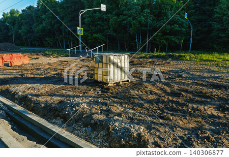 Construction site with water tank and muddy ground near forested roadside Construction site with water tank and muddy ground near forested roadside 140306877