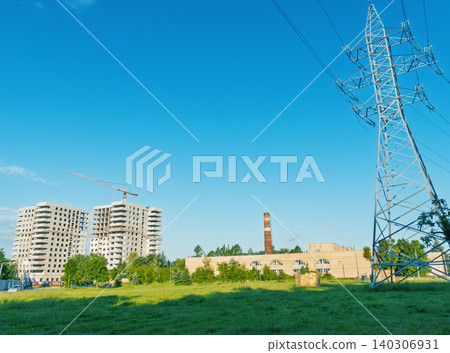 Urban construction site with power pylon and factory chimney under clear blue sky 140306931