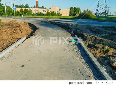 Newly constructed concrete sidewalk along suburban road under bright daylight Newly constructed concrete sidewalk along suburban road under bright daylight 140306988