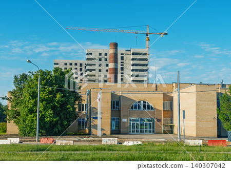 Industrial building frontage with construction site and tower crane Industrial building frontage with construction site and tower crane 140307042