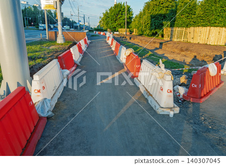 Temporary pedestrian pathway lined with red and white plastic barriers at roadside construction site Temporary pedestrian pathway lined with red and white plastic barriers at roadside construction site 140307045