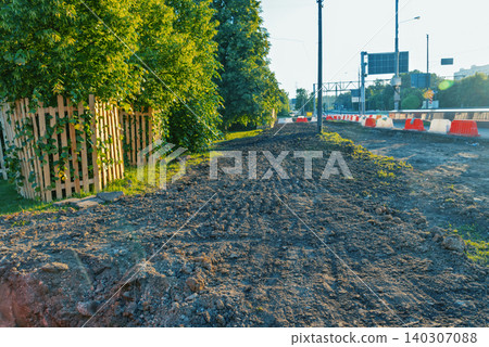 Sunlit roadside excavation beside leafy suburban fence Sunlit roadside excavation beside leafy suburban fence 140307088