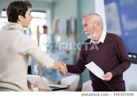 Smiling senior man makes deal, shaking hands with guy Smiling senior man makes deal, shaking hands with guy 140307096