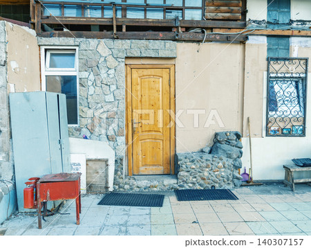 Worn wooden door set in aged mixed-material building facade Worn wooden door set in aged mixed-material building facade 140307157