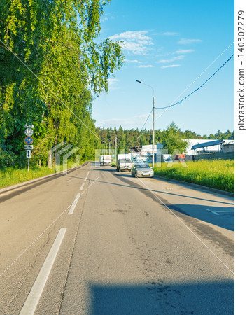Country road with parked commercial vehicles by green roadside trees Country road with parked commercial vehicles by green roadside trees 140307279
