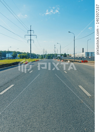 Empty suburban road with power lines and streetlights on a clear day 140307287