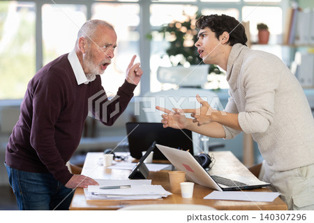 Elderly and young male colleague are arguing excitedly in office Elderly and young male colleague are arguing excitedly in office 140307296