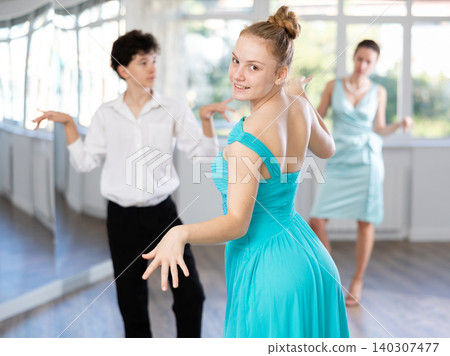 Smiling teenage girl practicing twist dance with boy in studio Smiling teenage girl practicing twist dance with boy in studio 140307477