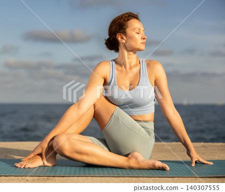 Ardha Matsyendrasana yoga pose - woman doing yoga On beach Ardha Matsyendrasana yoga pose - woman doing yoga On beach 140307555