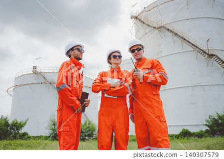Field engineering team consulting and reviewing inspection data at oil storage facility. Field engineering team consulting and reviewing inspection data at oil storage facility. 140307579