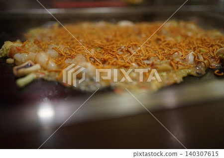 用 Baby Star 零食製作的文字燒,在熱板上烤得美味可口。 用 Baby Star 零食製作的文字燒,在熱板上烤得美味可口。 140307615
